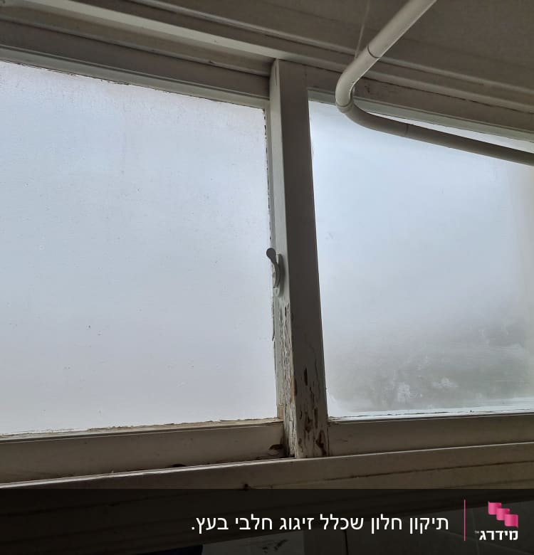 חלון זכוכית עם אדים ומסגרת עץ ישנה